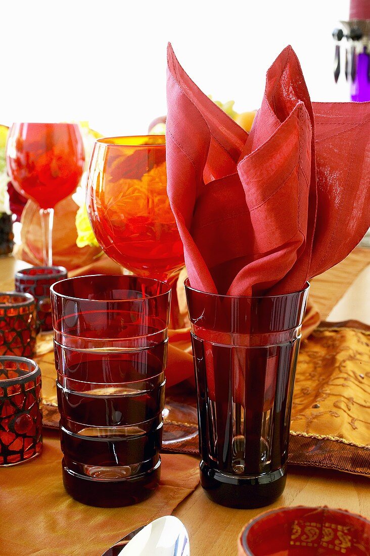 Red glasses, one with fabric napkin, on laid table