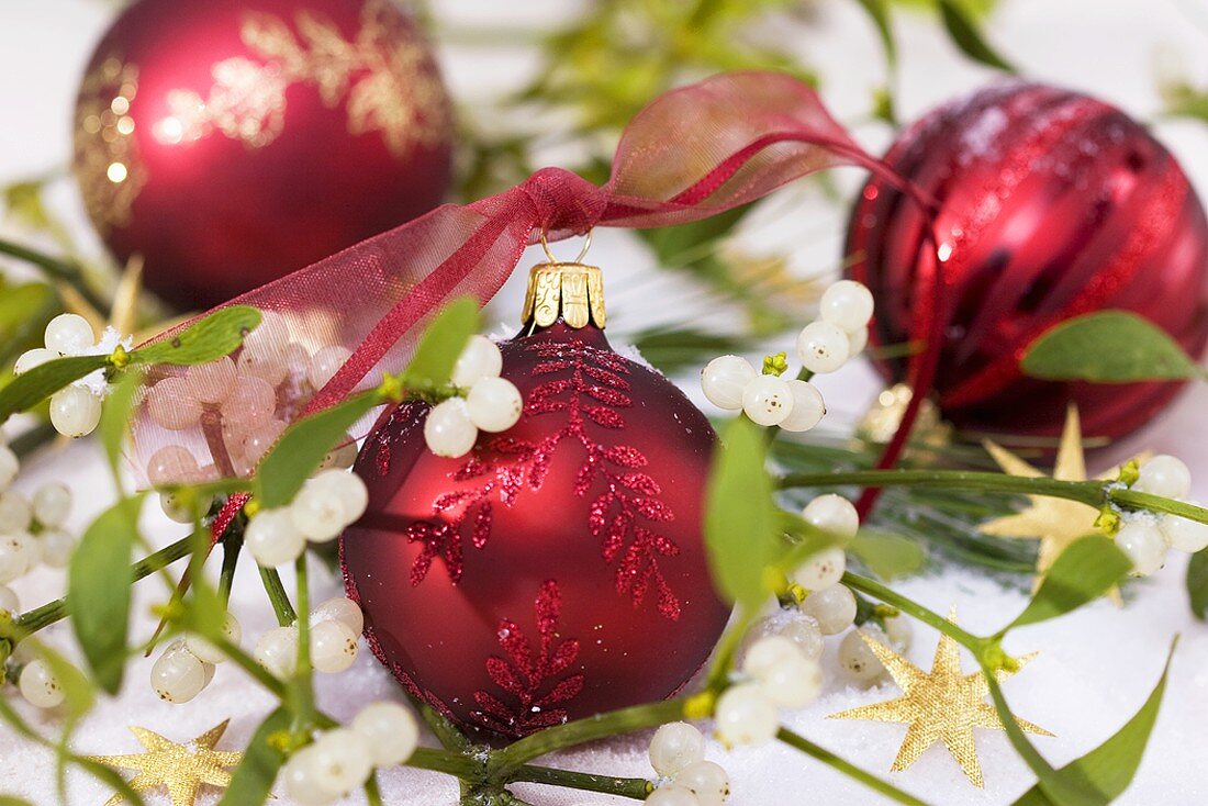 Red Christmas baubles amongst mistletoe and stars