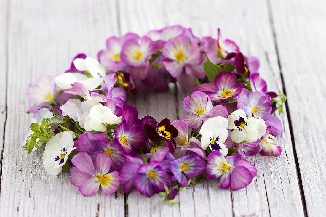 Wreath of horned violets on wooden background