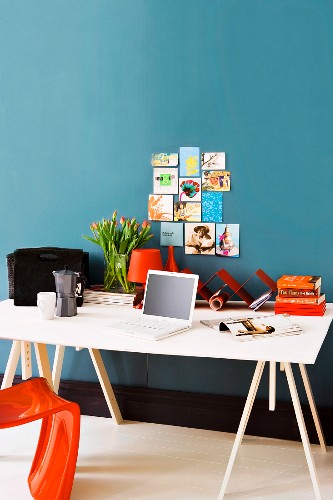 Einfacher Schreibtisch aus Holz mit leinwandüberzogener Arbeitsplatte an blauer Wand
