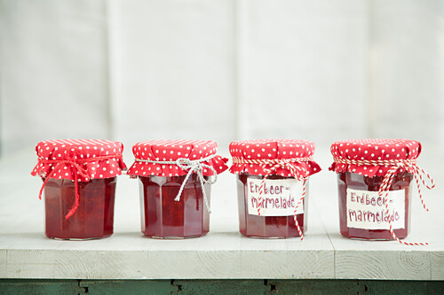 Jars of strawberry jam with homemade fabric lid covers
