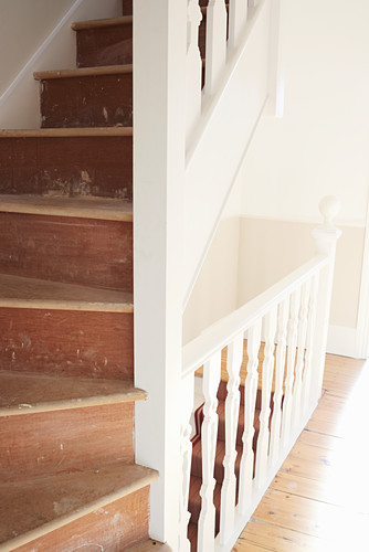 Old wooden staircase with worn treads and white balustrade
