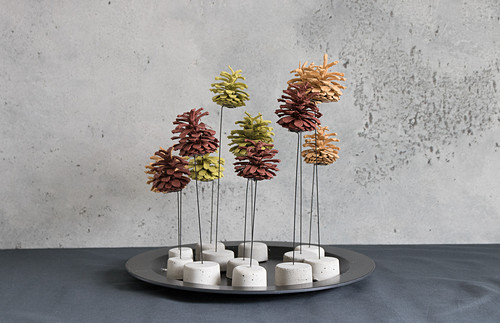 Painted pine cones on wire stands with concrete bases