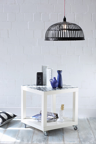 Side table with shelf on castors in front of white wall
