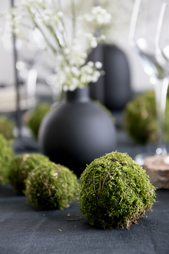Handmade moss balls on table set with black tablecloth
