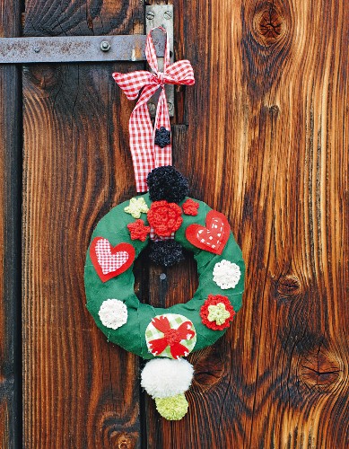 Hand-crafted Christmas wreath with love-heart motifs hung on wooden door