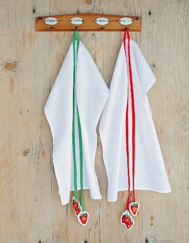 White tea towels decorated with strawberry-motif tags hanging from coloured ribbons