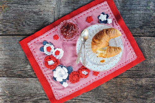 Breakfast on red and white hand-made place mat with crocheted flowers