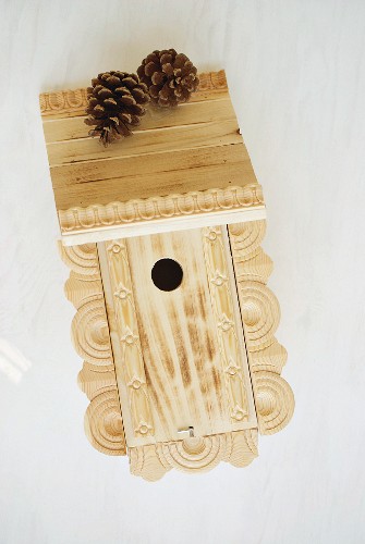 Traditional bird nesting box decorated with ornamental trim and pine cones