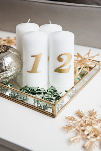 DIY Advent arrangement of candles, scattered decorations and straw stars on mirrored tray