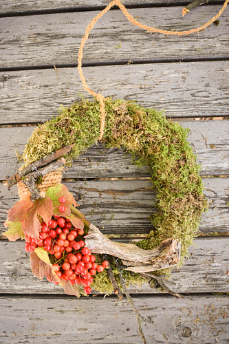 Moss wreath with viburnum berries and twigs on weathered wood