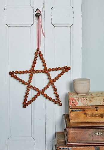 Star made of hazelnuts with decorative ribbon on door handle