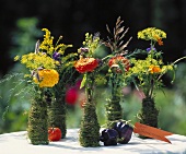 Zinnias in vases wrapped in moss, with label