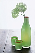Grüne Flasche mit Blumen und grünen Gläsern