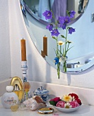 Vase of bluebells, marguerite by mirror and candle, flowers