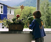 Girl watering flowers on balcony