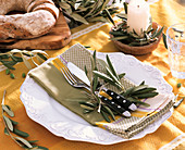 Gedeckter Tisch mit Olivenblättern dekoriert