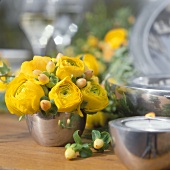 Gelbe Blumen in Silbervase als Tischdeko