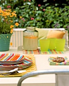 Summer table in garden with coloured plates & lemonade