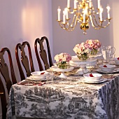 Festlich gedeckter Tisch mit weißem Geschirr und Rosen