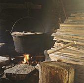 Cooking pot on open fire, axe and wood in old shack