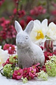 A stone rabbit surrounded by japonica and viburnums