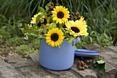Sunflowers with sprigs of blueberries and blackberries in an enamel pot