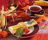 Autumnal place-setting with string of corn around napkin