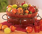 Pomegranates and ornamental cucumbers in glass bowl