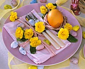 Easter place-setting with primulas, egg and sugar eggs