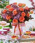 Arrangement of roses and lilac on table with strawberry tarts