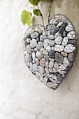 Wire heart filled with pebbles on wall