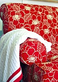 Upholstered red floral-patterned chair with woollen throw