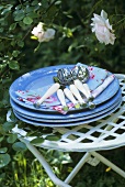 Pile of plates with napkins and cutlery on a garden table