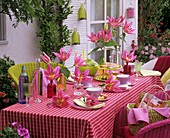 Gedeckter Tisch mit Lilien und Flaschen dekoriert