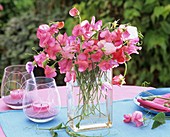 Bunch of sweet peas in square vase and windlights