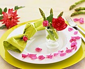 Place-setting decorated with green asparagus and roses