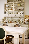 Crockery and ornaments on antique, white-painted kitchen dresser