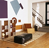 Kleine Sitzecke in offenem Wohnraum mit Leder-Sitzpolster und Regalsystem vor grafischen Mustern an der Wand