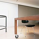 Schwarzer Stuhl mit Stahlrohrgestell an modernem Holztisch mit Rollen