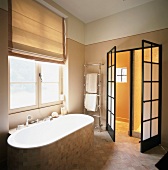 Badezimmer mit schwarzgerahmten Milchglastüren neben einem Handtuchtrockner und Wanne vor dem Fenster
