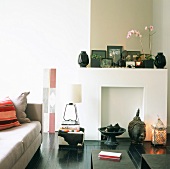Wohnraum mit asiatischer Deko auf dem schwarz lackierten Dielenboden und in der stillgelegten Kaminnische