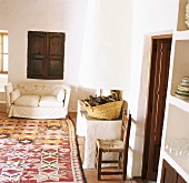Rustikaler, weiss verputzter Wohnraum mit Teppich im Kelimmuster und Sofa vor dem gemauertem Kamin