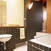 Braun und weiss gefliestes Badezimmer mit grossem, integriertem Spiegel und Stufen nach oben