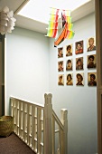 Stairwell with colourful mobile and gallery of portraits on wall