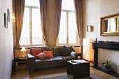 Helles Wohnzimmer mit schwarzer Ledercouch und Spiegel mit Goldrahmen über ehemaligem offenen Kamin