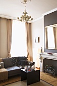 Moderner Wohnraum mit grauer Ledercouch , gemütlichen Tagesdecken und mit großem Spiegel über dem offenen Kamin