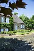 Grün Bewachsenes Landhaus mit kleinem, dekorativ gestalteten Vorgarten
