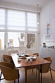 Wooden chairs with curved backrests and torso sculpture on wide dining table