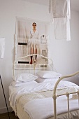 Vintage-Bett mit weißem Metallgestell und Frauenfotografie auf Stoff über dem Bett hängend